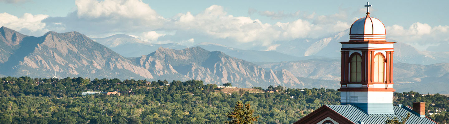 Aerial photo of Regis Northwest Campus featuring Main Hall and a mountain landscape.